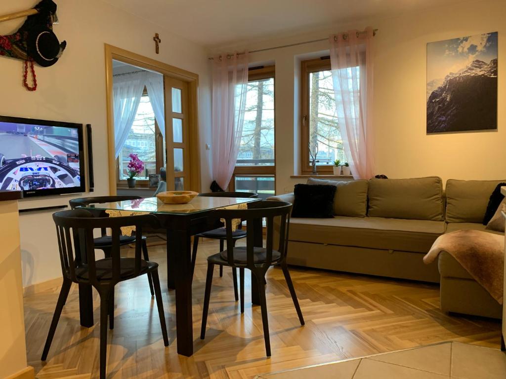 een woonkamer met een tafel en stoelen en een bank bij Apartament Góralka in Zakopane
