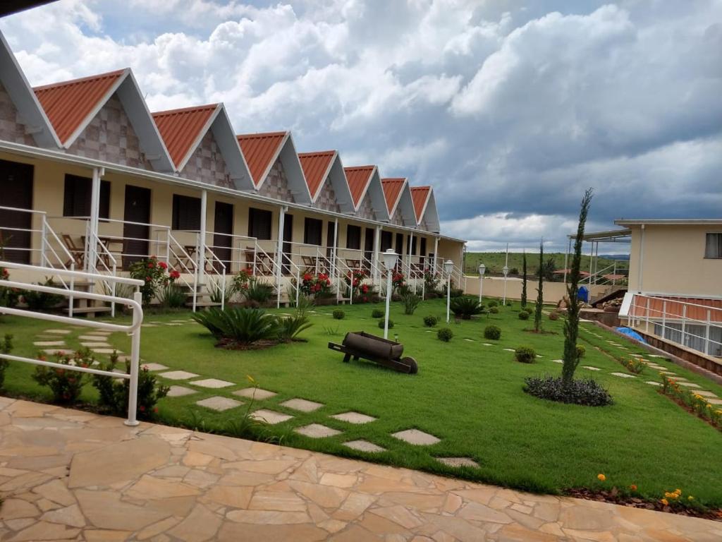 un patio de un complejo con un banco en el césped en Pousada Canto dos Canários en Socorro