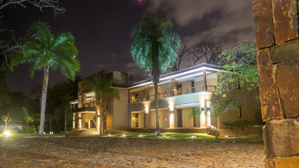 a house with two palm trees in the night at Pirayu Hotel & Resort in Puerto Iguazú