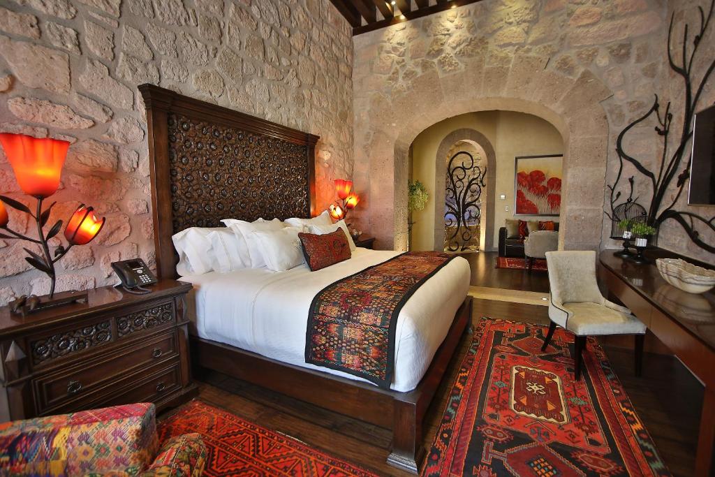 a bedroom with a large bed and a stone wall at Hotel De La Soledad in Morelia
