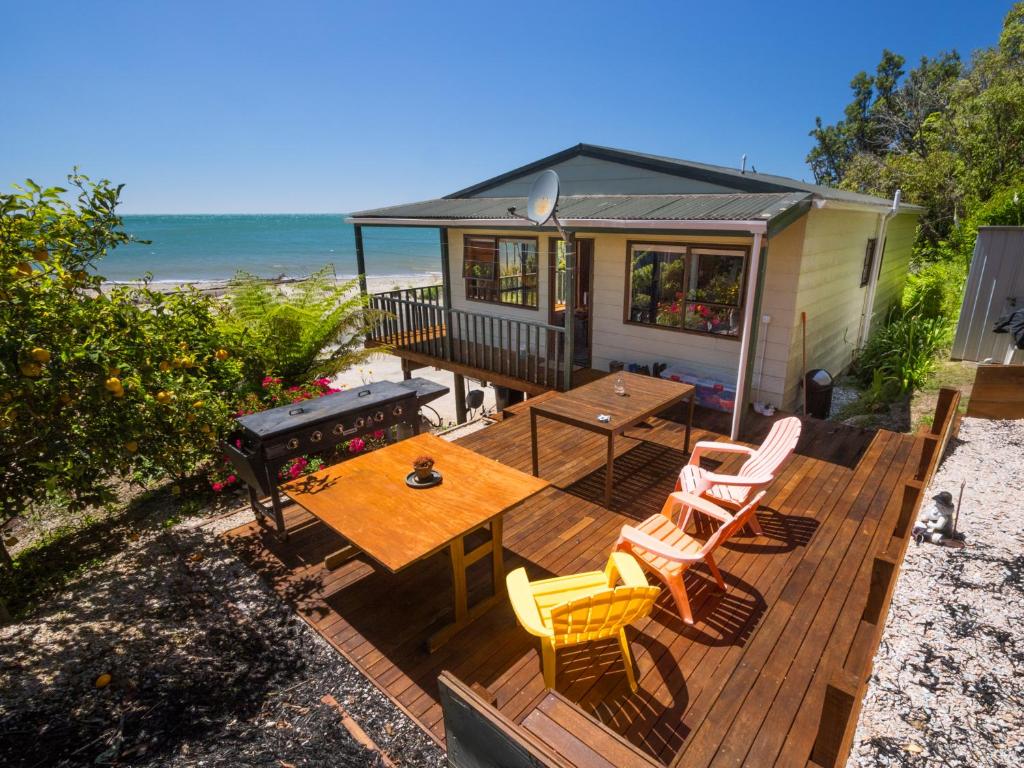 a deck with a picnic table and chairs on the beach at Tidal Treasure - Collingwood Holiday Home in Collingwood
