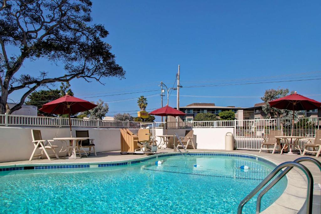 a swimming pool with chairs and umbrellas on a building at Motel 6-Monterey, CA in Monterey