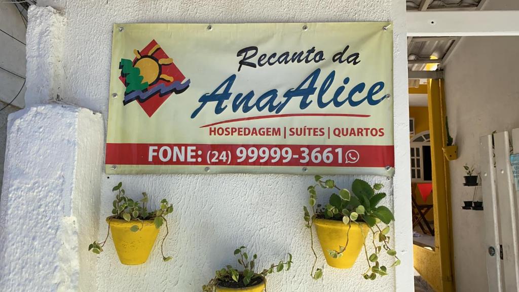 a sign on the side of a building with potted plants at Pousada Recanto da Ana Alice in Abraão