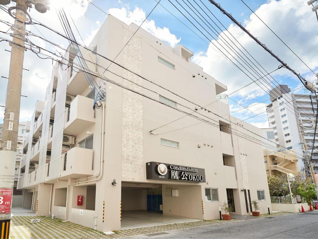 a white building with a sign on the side of it at Tenpoint Hotel OKOU in Naha