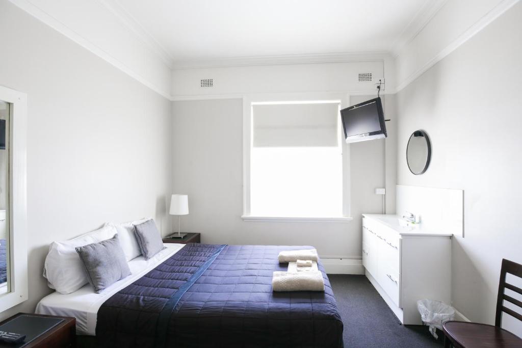 
a bedroom with a white bed and white walls at Hotel Gosford in Gosford
