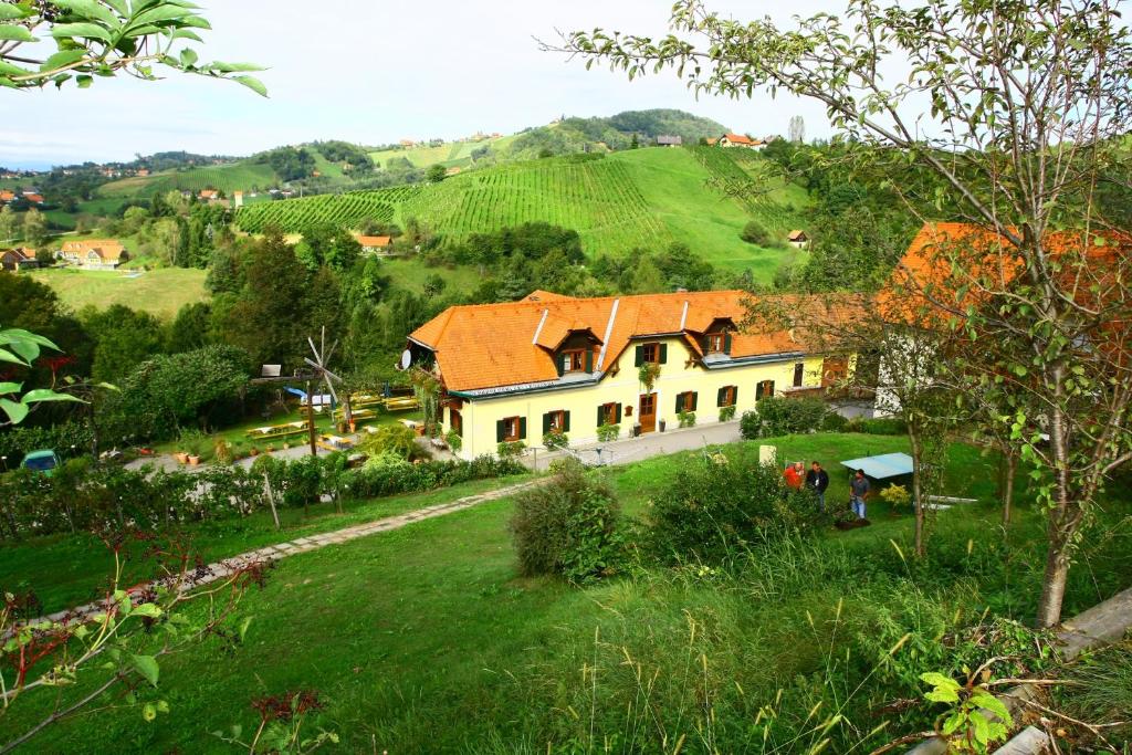 ein Haus auf einem Hügel mit einem grünen Feld in der Unterkunft Weingut Schlafgut Genussgut Lorenz in Kitzeck im Sausal