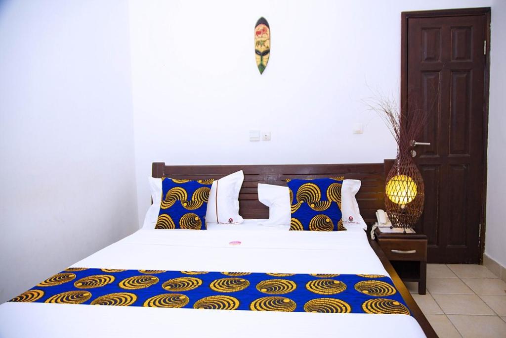 1 dormitorio con 1 cama grande con almohadas azules y amarillas en Cypa Hotel en Abiyán