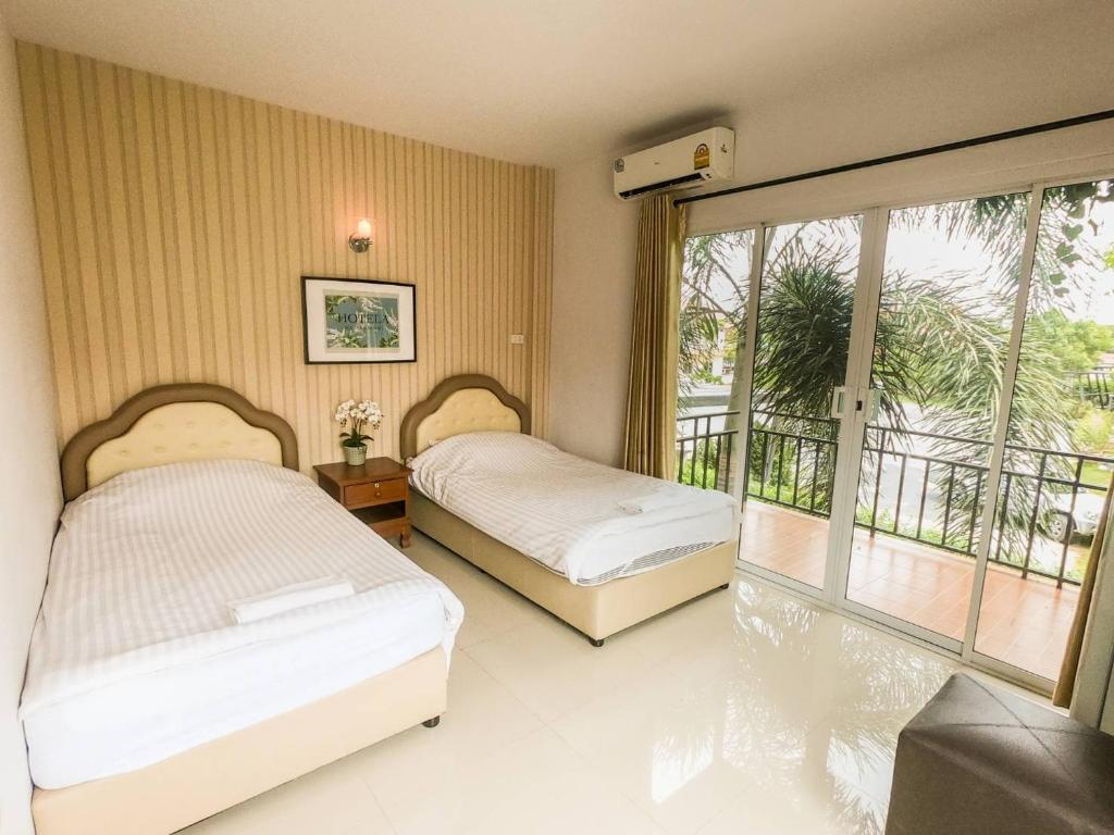 una camera con 2 letti e un balcone di Hotela Boutique Resort a Suphanburi