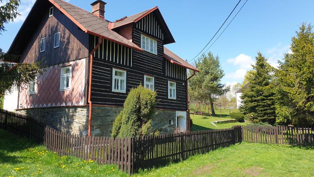 une ancienne maison noire avec une clôture en bois dans l'établissement Chalupa na Jelení, à Jelení