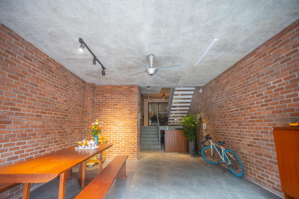 a room with a brick wall and a table and a bike at CRIN.HOUSE Homestay in Hanoi