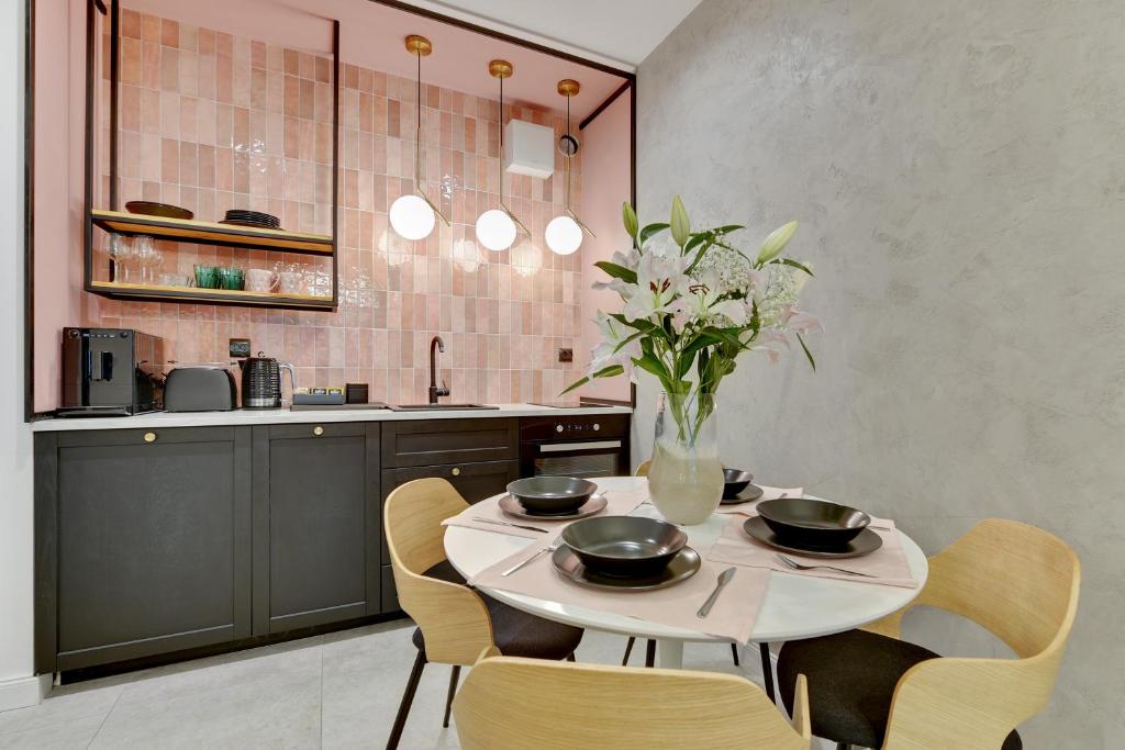 a kitchen with a table with chairs and a vase of flowers at Downtown Apartments Aura III Apartments & Parking in Gdańsk