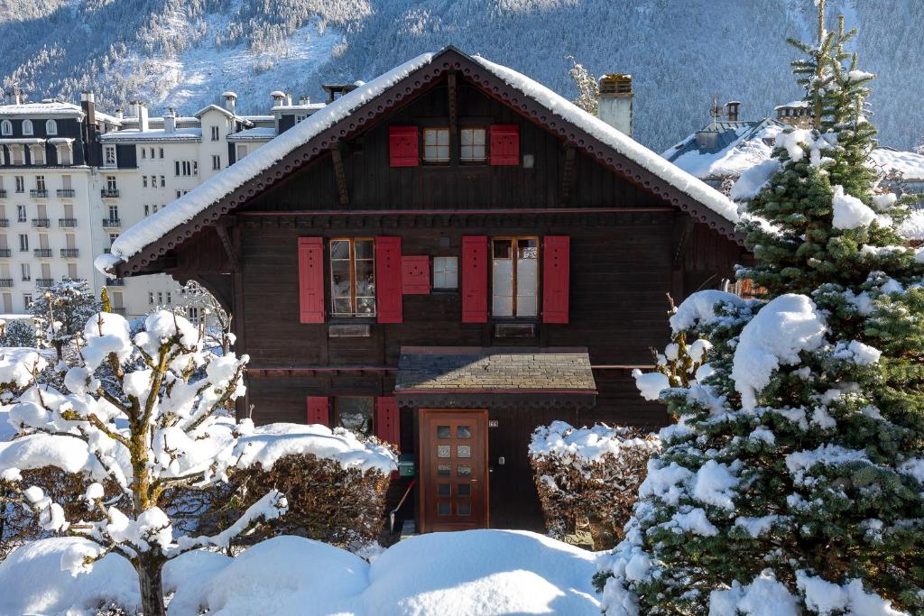 a wooden house with red shutters in the snow at Chalet Clos 66 in Chamonix