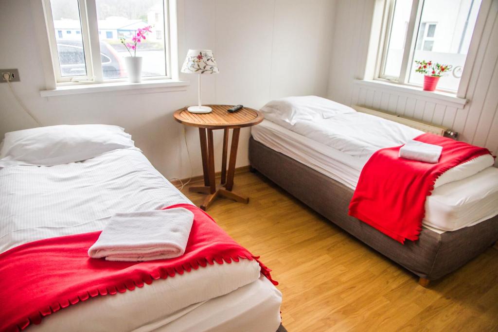 2 łóżka w pokoju ze stołem i 2 oknami w obiekcie Guesthouse Sunnuhóll w mieście Vestmannaeyjar