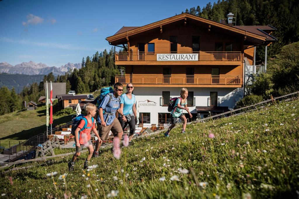 un grupo de personas corriendo por una colina delante de un edificio en Berggasthof Hochzeigerhaus, en Jerzens