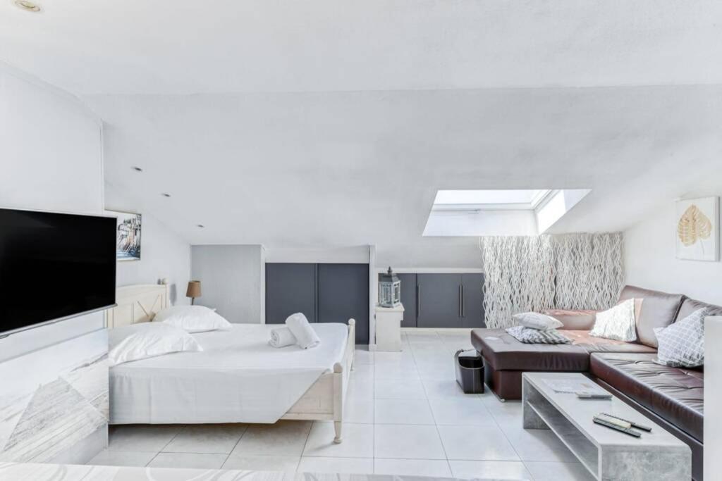 un salon blanc avec un canapé et une télévision dans l'établissement C009-Duplex avec vue sur mer et piscine, à Cannes