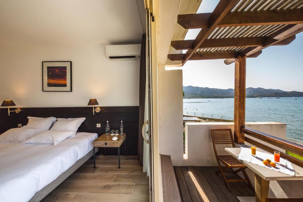 a bedroom with a bed and a view of the water at Hôtel La Roya in Saint-Florent
