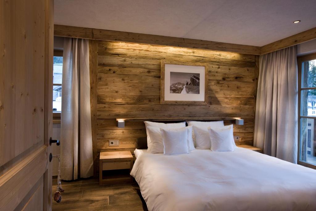 1 dormitorio con cama blanca y pared de madera en Chalet Corvara, en Corvara in Badia