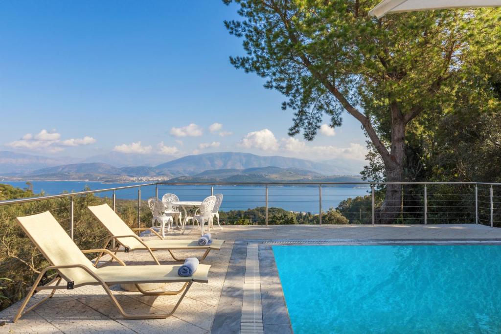 a patio with chairs and a swimming pool with a view of the water at Villa Leondari by Rodostamo Collection in Ágios Stéfanos