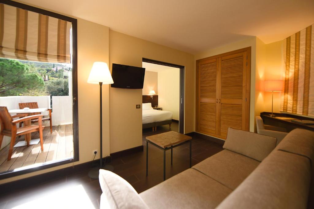a living room with a couch and a bedroom at Hôtel La Roya in Saint-Florent
