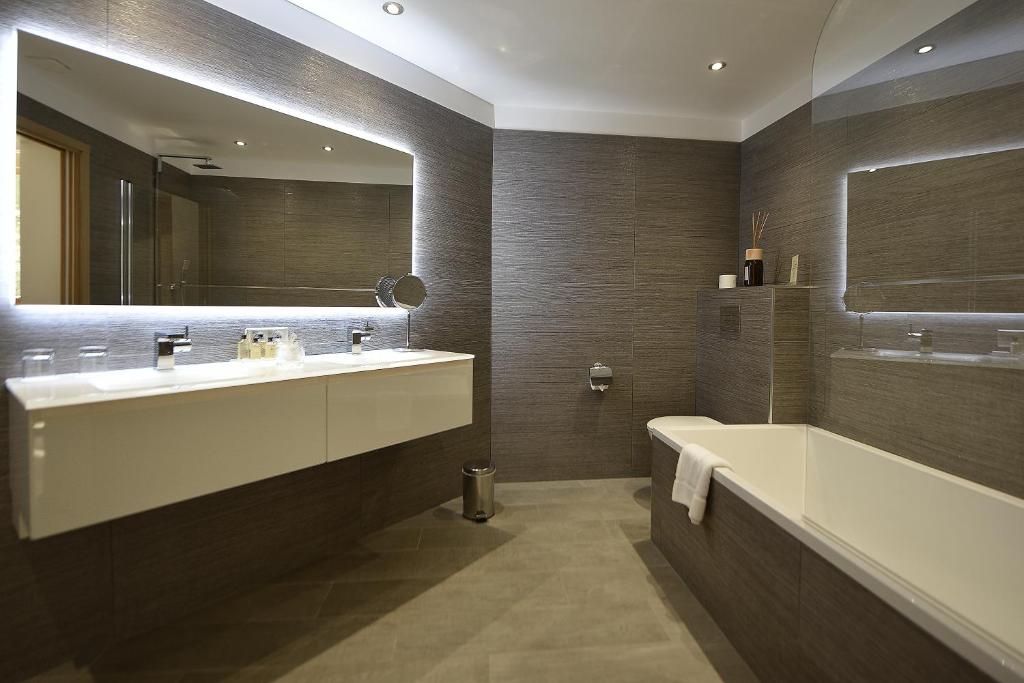 a bathroom with a sink and a tub and a mirror at Hôtel La Roya in Saint-Florent