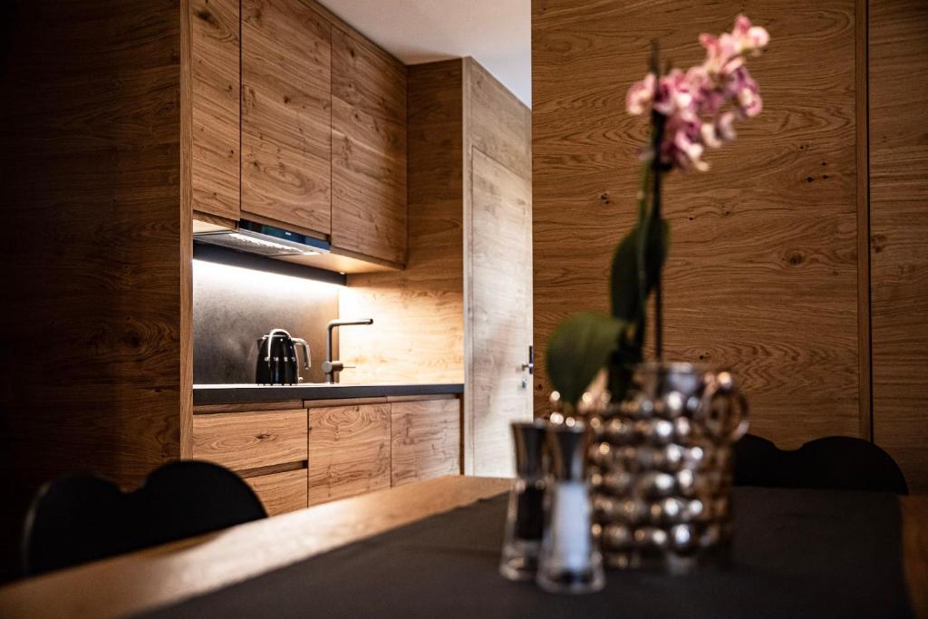 a kitchen with a table with a vase of flowers at Hotel & Appartements Alpenresidenz Viktoria inklusive Sommer Stubai Super Card in Neustift im Stubaital