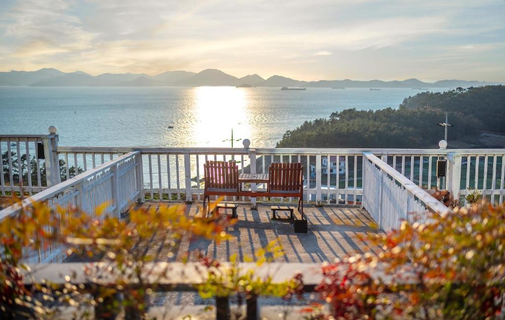 - un balcon avec deux chaises et une vue sur l'eau dans l'établissement Namhae Whale's Dream, à Namhae