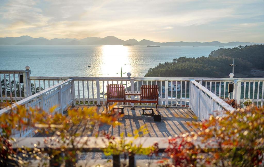 a balcony with two chairs and a view of the water at Namhae Whale's Dream in Namhae