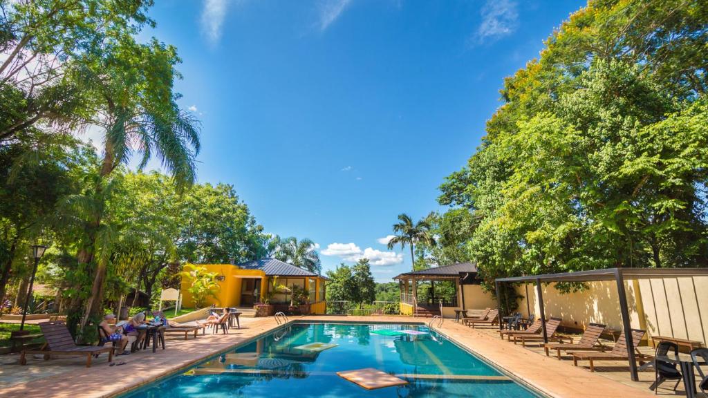 uma piscina com pessoas sentadas em cadeiras à sua volta em Pirayu Lodge Resort em Porto Iguaçu