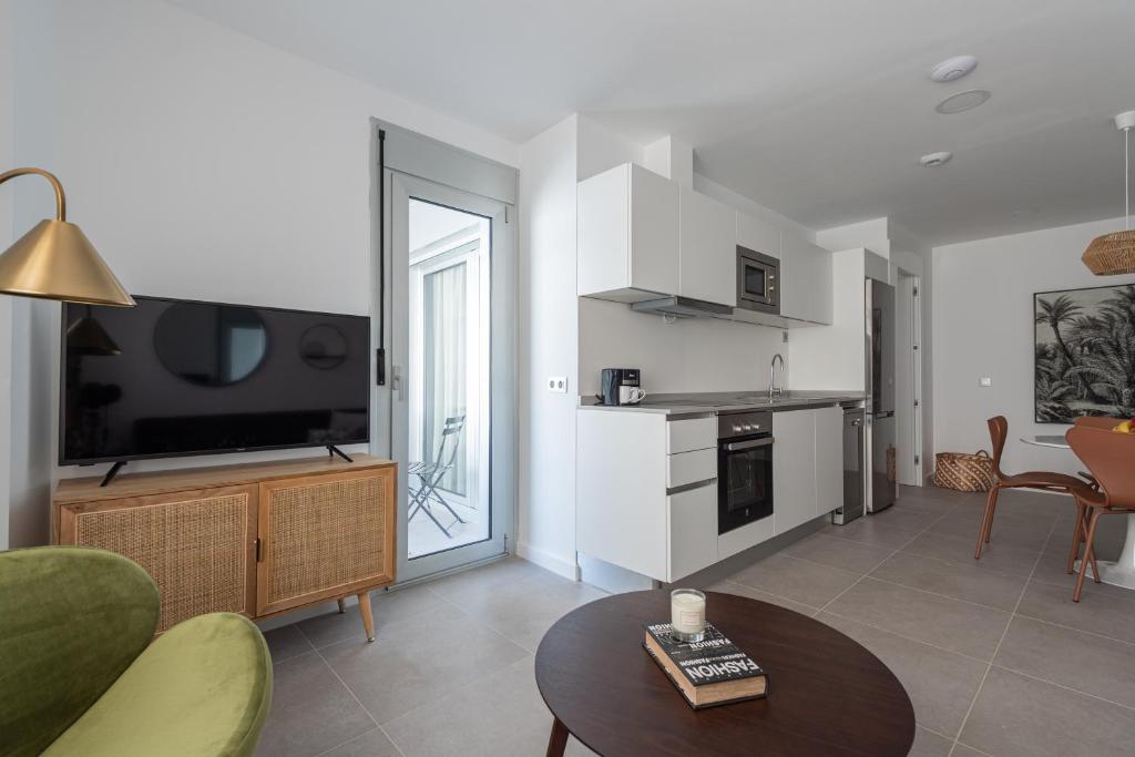 a living room with a tv and a kitchen with a table at Royal Flats in Las Palmas de Gran Canaria