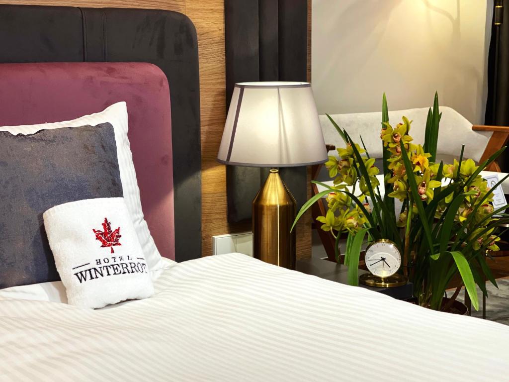 a bedroom with a bed with a lamp and flowers at Hotel Winterrot in Karlsruhe