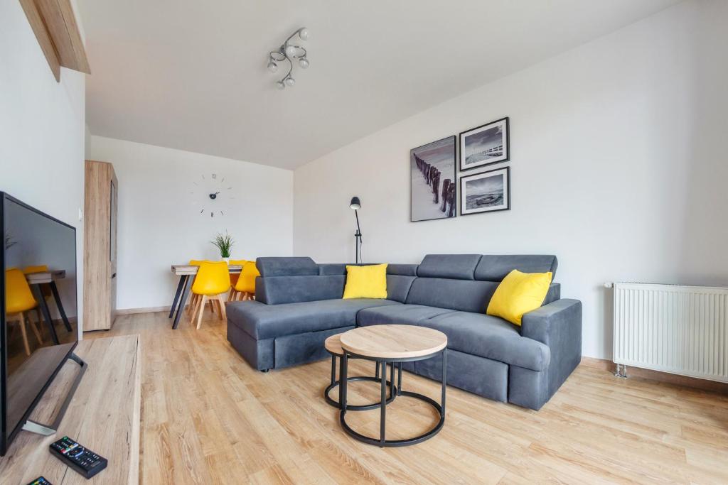 a living room with a blue couch and yellow pillows at Apartamenty Sun & Snow Spektrum in Gdańsk