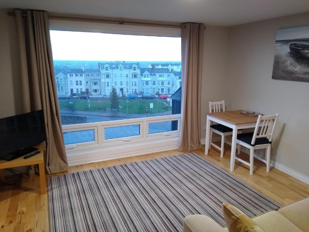 a living room with a large window and a table at The Loft Guest Apartment in Portstewart