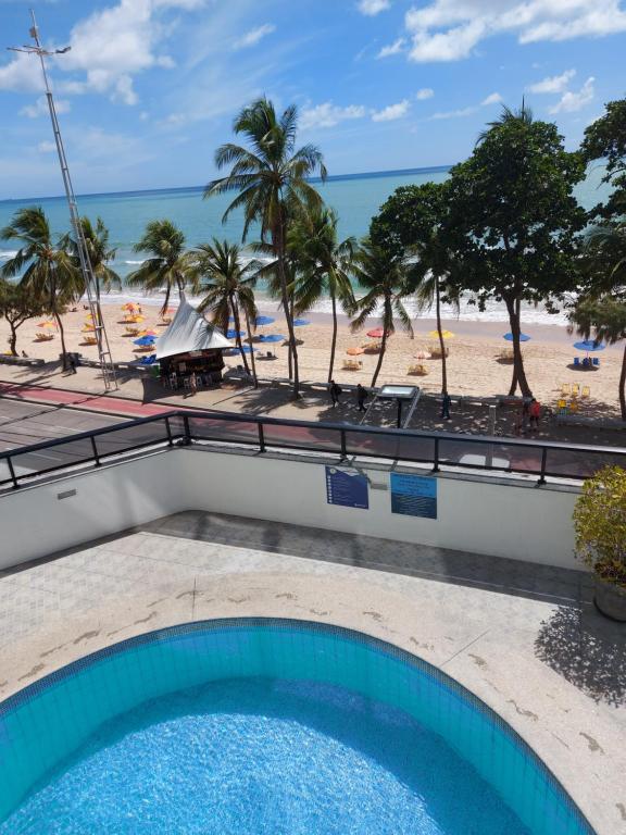 uma piscina com praia ao fundo em Hotel Euro Suíte Recife Boa Viagem no Recife