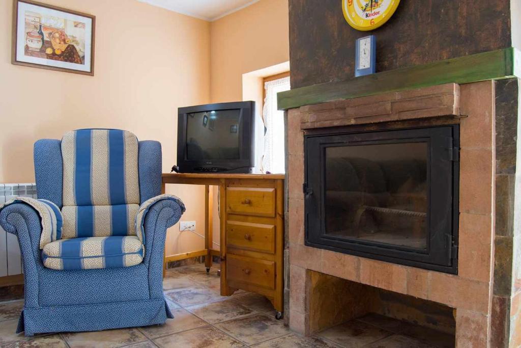 een woonkamer met een open haard en een televisie bij Casa rural con jacuzzi in La Parrilla