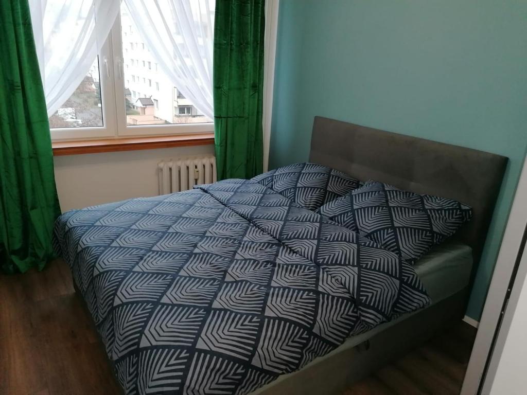 a bed with a comforter and a window at Mieszkanie Konin Zatorze in Konin