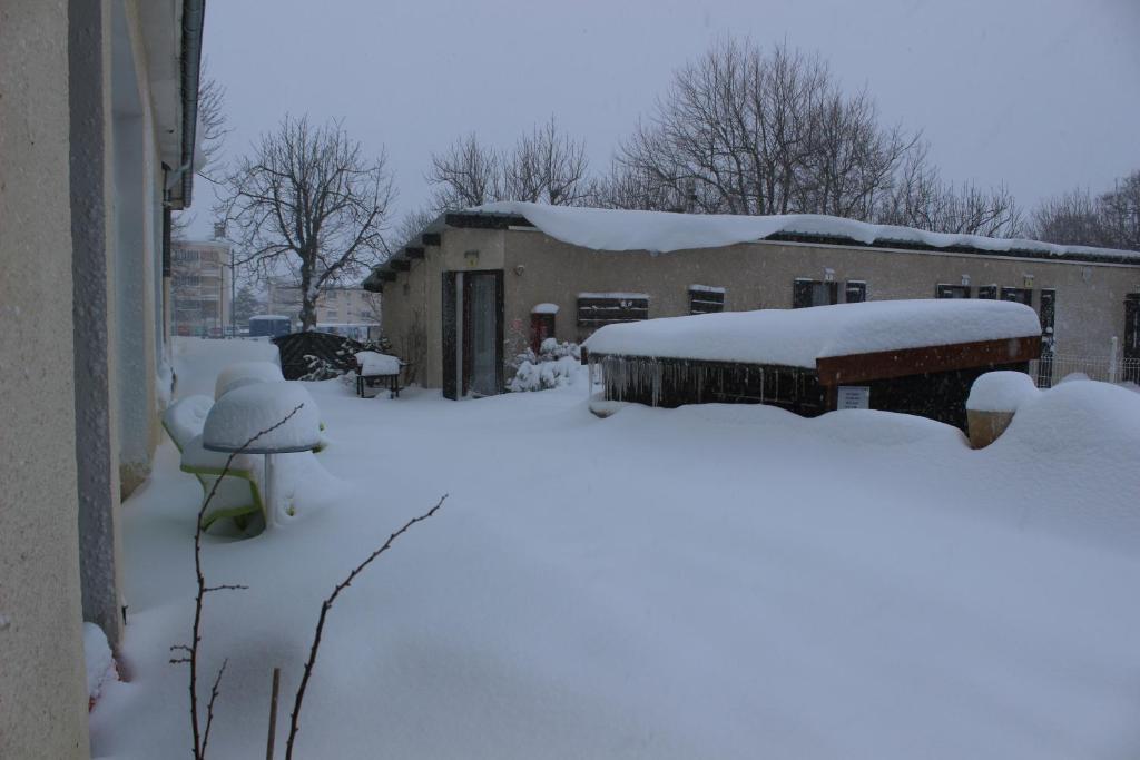 un patio cubierto de nieve junto a un edificio en Hotel Le Connetable, en Saint-Bonnet-en-Champsaur