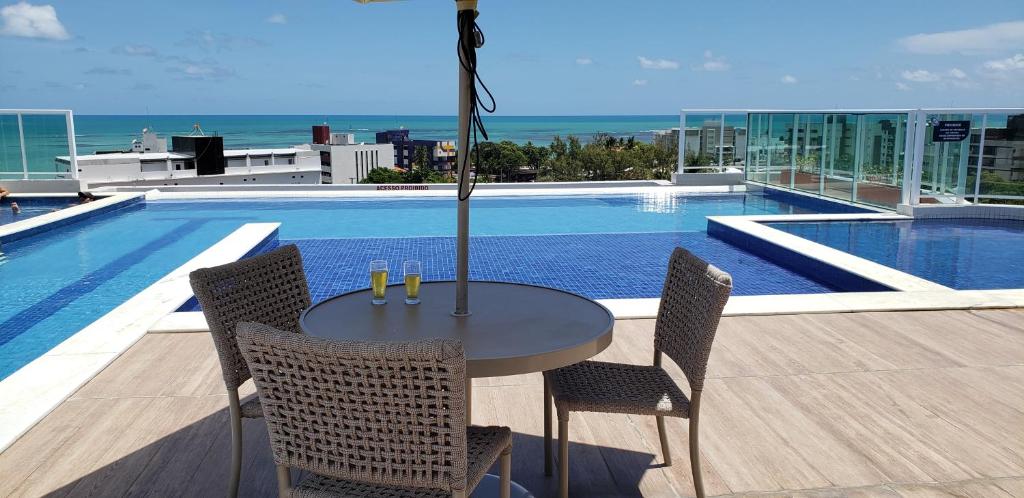a table and chairs next to a swimming pool at EXCELENTE FLAT 2 QUARTOS no BESSA in João Pessoa