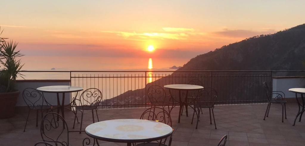 a balcony with tables and chairs and a sunset at Le Marelle in Furore