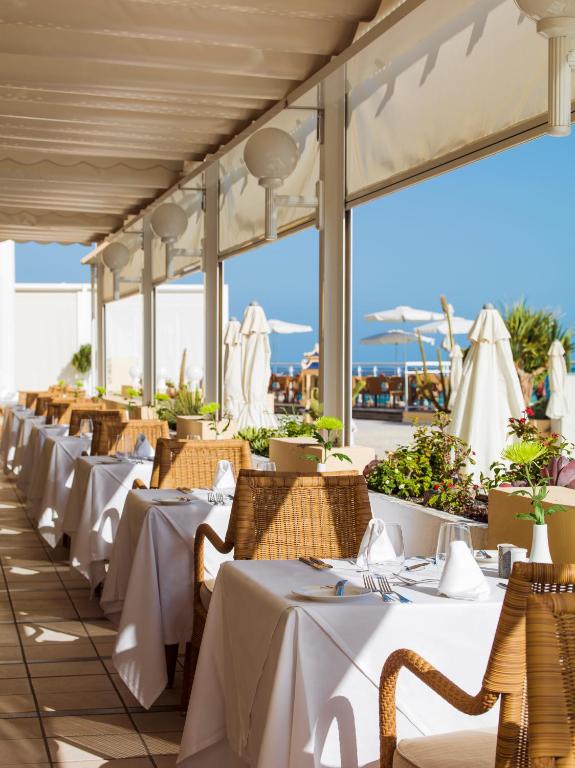 a row of tables with white table cloths on a restaurant at XQ El Palacete in Morro del Jable