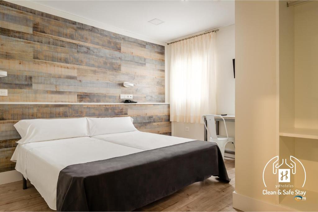 1 dormitorio con 1 cama y pared de madera en YIT Casablanca, en Granada
