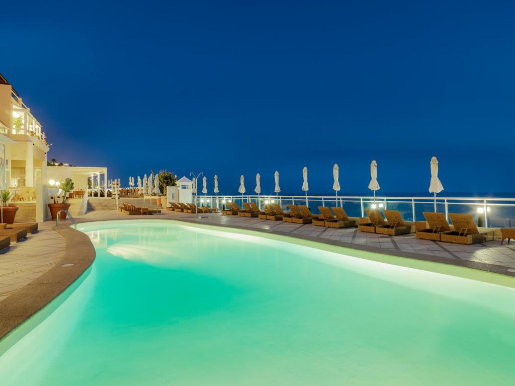 a swimming pool at night with chairs and umbrellas at XQ El Palacete in Morro del Jable