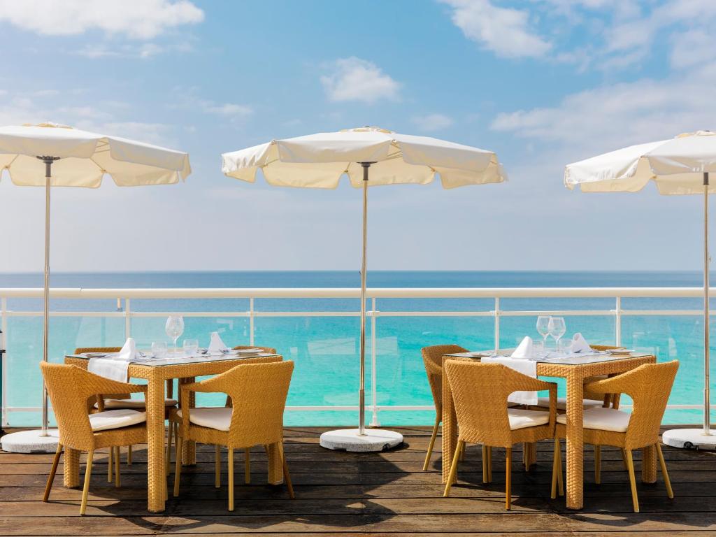 a table with chairs and umbrellas on a deck at XQ El Palacete in Morro del Jable