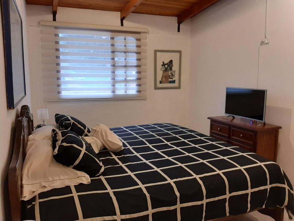 1 dormitorio con 1 cama y TV en La Posada del Aromito - Suite, en Quito
