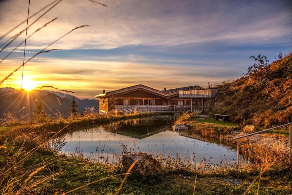 ein Haus auf einem Hügel mit einem Teich davor in der Unterkunft Chalet Stern in Sterzing