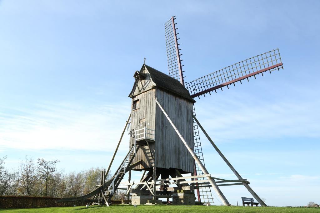 a wooden windmill in a field with a blue sky at B&amp;B Leonie in Alveringem