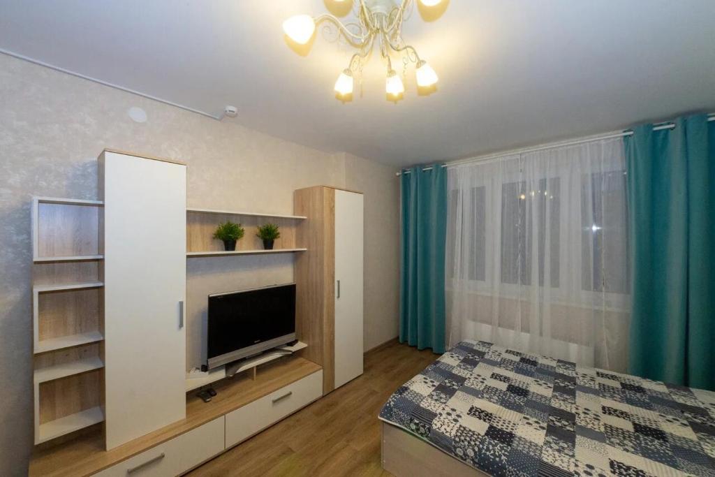 1 dormitorio con 1 cama y TV de pantalla plana en Апартаменты en Nizhni Nóvgorod