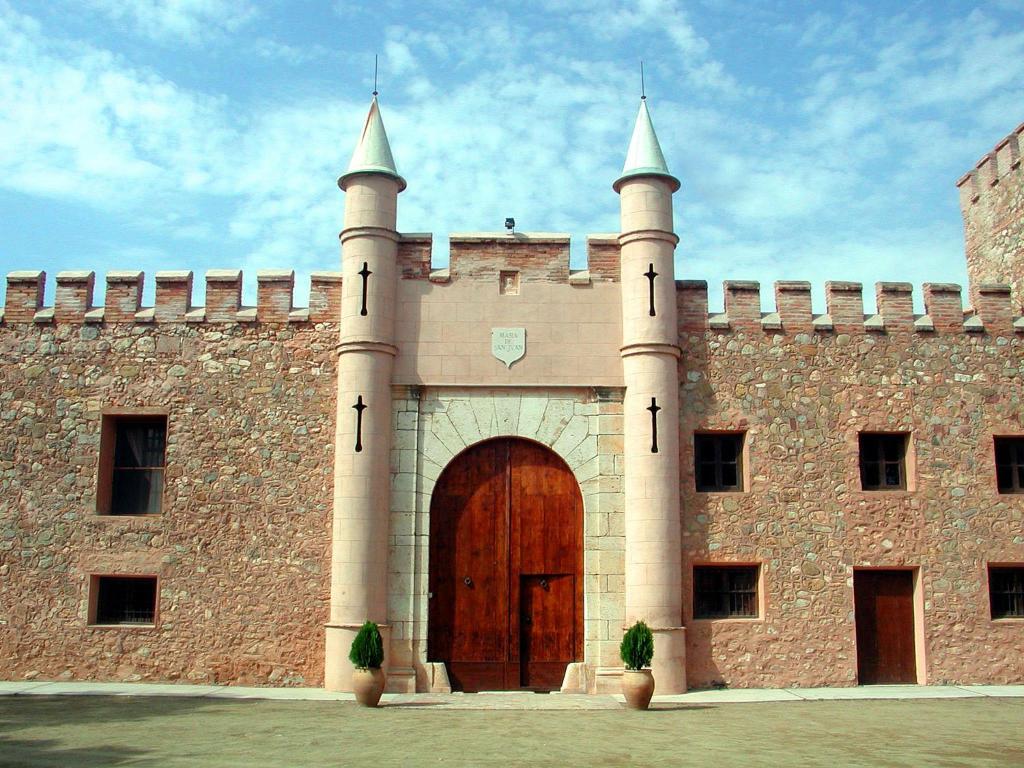 a large brick building with a large wooden door at Masía de San Juan Casas Rurales con piscina, aire acondicionado y vistas a la montaña in Segorbe