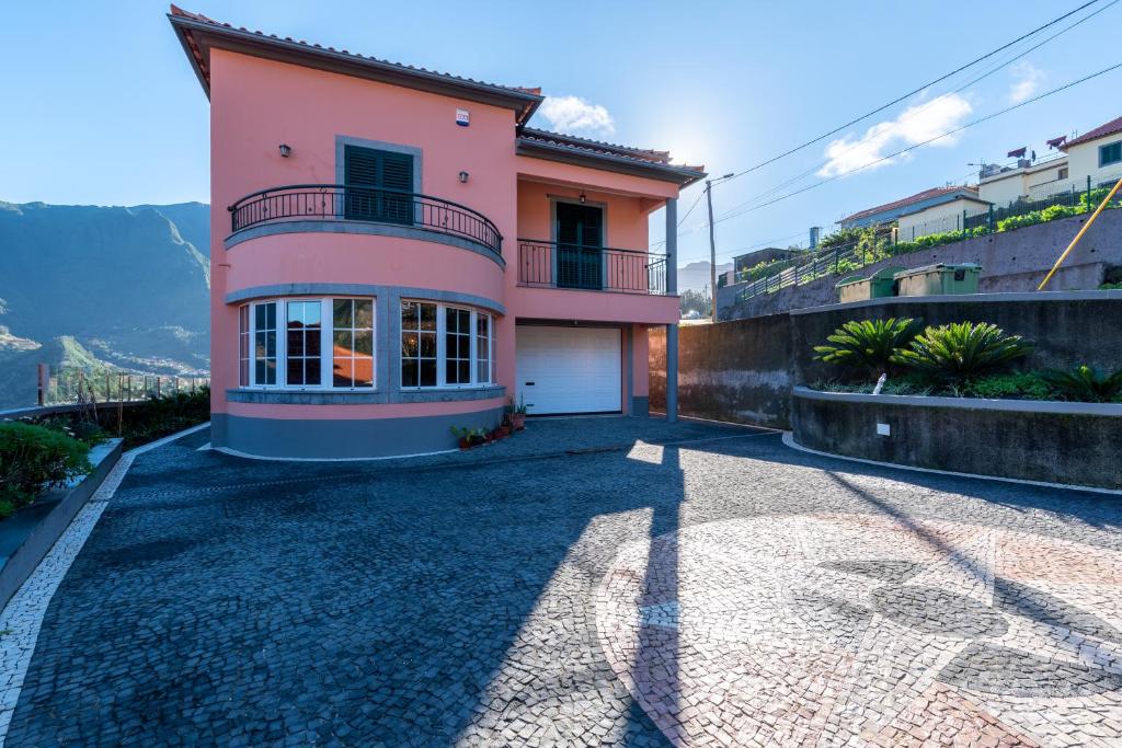 une maison rose avec un balcon sur une colline dans l'établissement Cristina Grand, à São Vicente