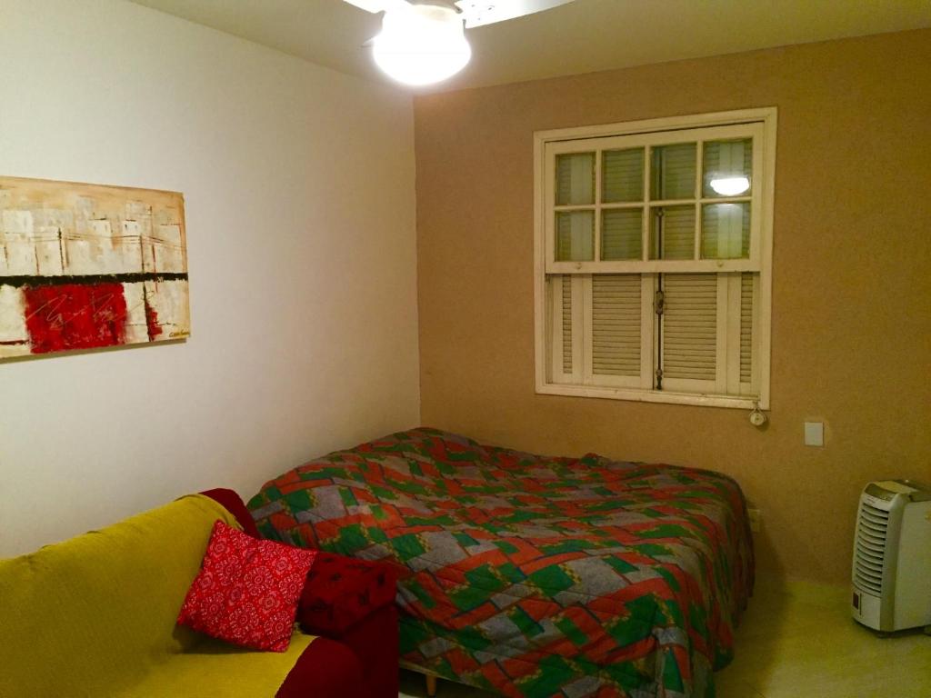 ein Schlafzimmer mit einem Bett, einem Fenster und einer Couch in der Unterkunft Kitinete confortável frente ao mar in Santos