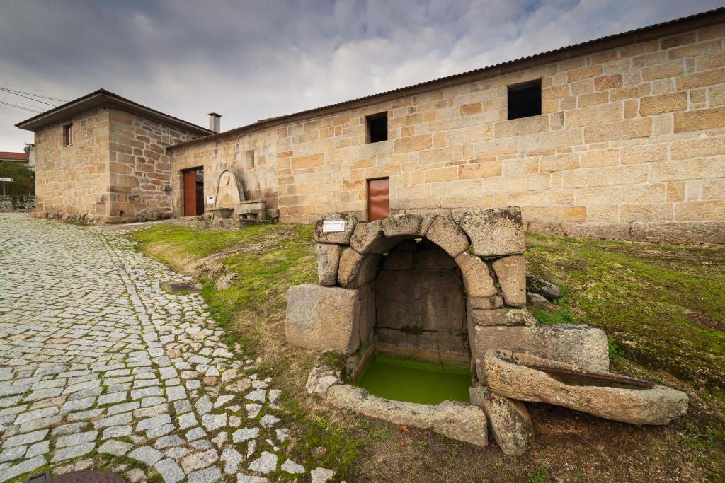 Casa do Parente في Sabroso: مبنى من الطوب وامامه حفرة ماء